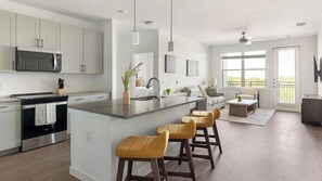 Eine moderne Küche mit Kochinsel, Barhocker und einem Essbereich mit Sofa und Couchtisch.