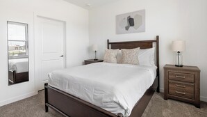 A bedroom with a bed, a nightstand, a lamp, a mirror, and a wall-mounted artwork. - Landing | Chic 1BD, Gym, Courtyard (Dallas)