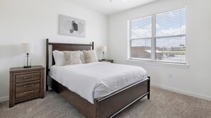 A bedroom with a bed, nightstands, a lamp, a window with blinds, and a wall-mounted artwork. - Landing | Amazing 1BD, Clubhouse, Pool (Dallas)