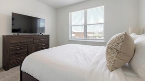 A bedroom with a bed, a dresser, a television, and a window with blinds. - Landing | Amazing 1BD, Courtyard, Clubhouse (Dallas)