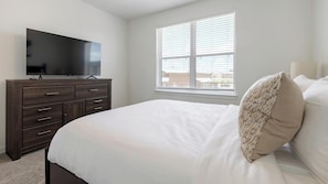 A bedroom with a bed, a dresser, a television, and a window with blinds. - Landing | Amazing 1BD, Courtyard, Clubhouse (Dallas)