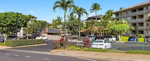 A hotel entrance with a sign, parked cars, and a well-maintained lawn. - 2-bedroom, 2-bathroom resort at Worldmark Kihei Hawaii (Kihei)