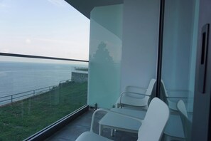 A balcony with a view of the sea, a glass wall, and white chairs. - Mandrati Room 04 for 3 • Sea View & Heated Pool (Sarpi)