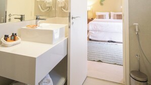 Une salle de bain moderne avec un grand miroir, un lavabo blanc et un sèche-cheveux.