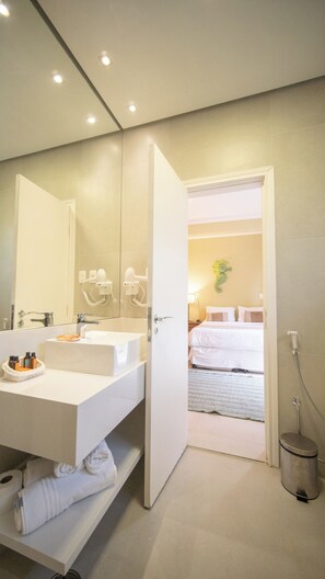 A modern bathroom with a large mirror, a white sink, and a hairdryer. - Pousada Montão Do Trigo (São Sebastião)