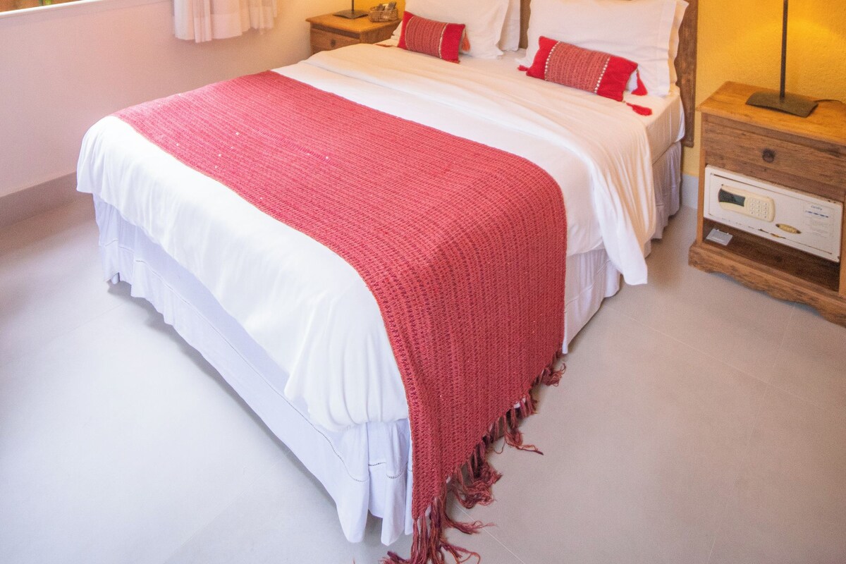 A bedroom with a bed, bedside tables, a wall-mounted shelf, and an air conditioning unit.