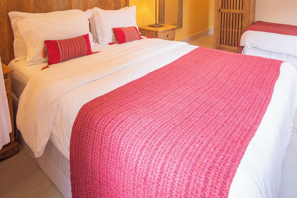A hotel room with a large bed, a wooden headboard, a nightstand with a lamp, and a wardrobe.