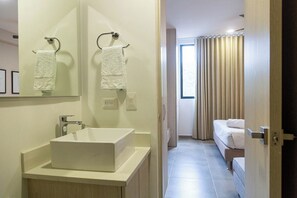 Un baño moderno con un lavamanos grande, dos toalleros y un espejo.