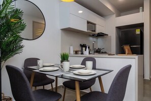 Una cocina moderna con comedor, que incluye un espejo redondo, una planta en maceta y una mesa preparada para dos.