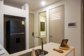 Una cocina moderna con refrigerador empotrado, un lavamanos y una tabla de cortar de madera.
