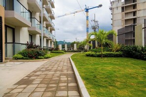 A residential building with a paved walkway, greenery, and a construction crane in the background. - Apartamento familiar en Gaira con vista al jardin (Gaira)