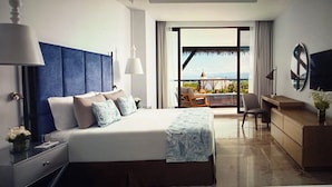 Quarto de hotel com cama grande, escrivaninha, cadeira e varanda com vista.