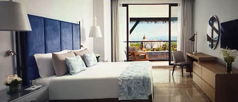 A hotel room with a large bed, a desk, a chair, and a balcony with a view.