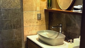 Casa de banho com lavatório de cuba, espelho e porta-toalhas.