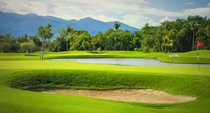 A golf course with a sand bunker, water hazard, and a flagstick. - Kingdom of the Sun, 2 BR/3 Baths for PGA Golf Tournament,Puerto Vallarta, Mexico (Puerto Vallarta)