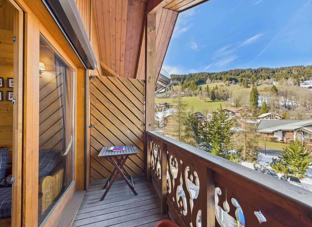 Un balcon en bois offrant une vue sur la ville et la forêt.