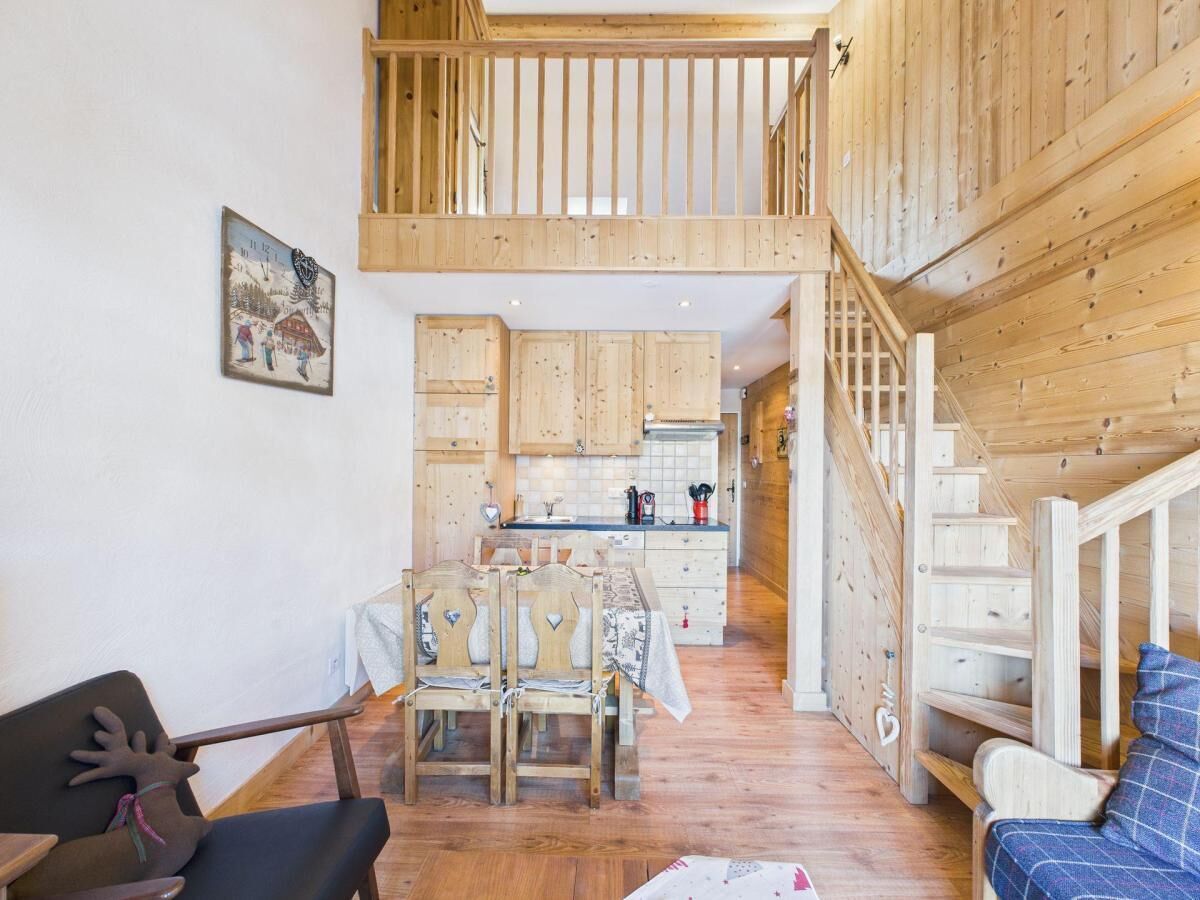 A wooden interior with a dining area, kitchen, and staircase.