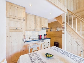 A kitchen with wooden cabinets, a dining table with a patterned tablecloth, and a staircase leading to an upper level. - 2nd floor, balcony, parking, tv, 35m², Les Gets (Les Gets)