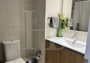 A bathroom with a toilet, sink, and mirror.
