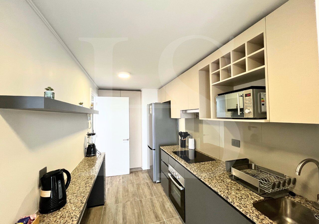 Una cocina moderna con encimeras de granito, electrodomésticos de acero inoxidable y estanterías empotradas.