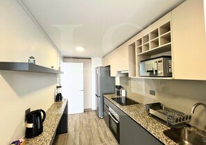 A modern kitchen with granite countertops, stainless steel appliances, and built-in shelving.
