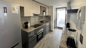 A modern kitchen with a refrigerator, stove, microwave, and a phone on the wall.
