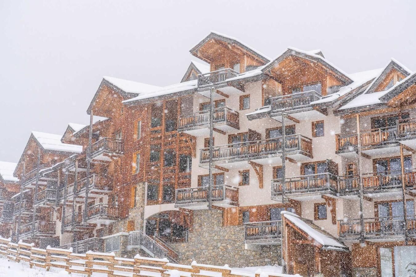 A multi-story hotel with balconies and a stone facade, surrounded by snow.