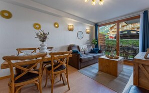 A room with a dining table, chairs, a sofa, and a coffee table. There are wall decorations and a view of the outside. - 20m from ski lifts, floor -1, swimming pool, sauna, terrace, tv, ski locker, 34m², Les Orres (Les Orres)