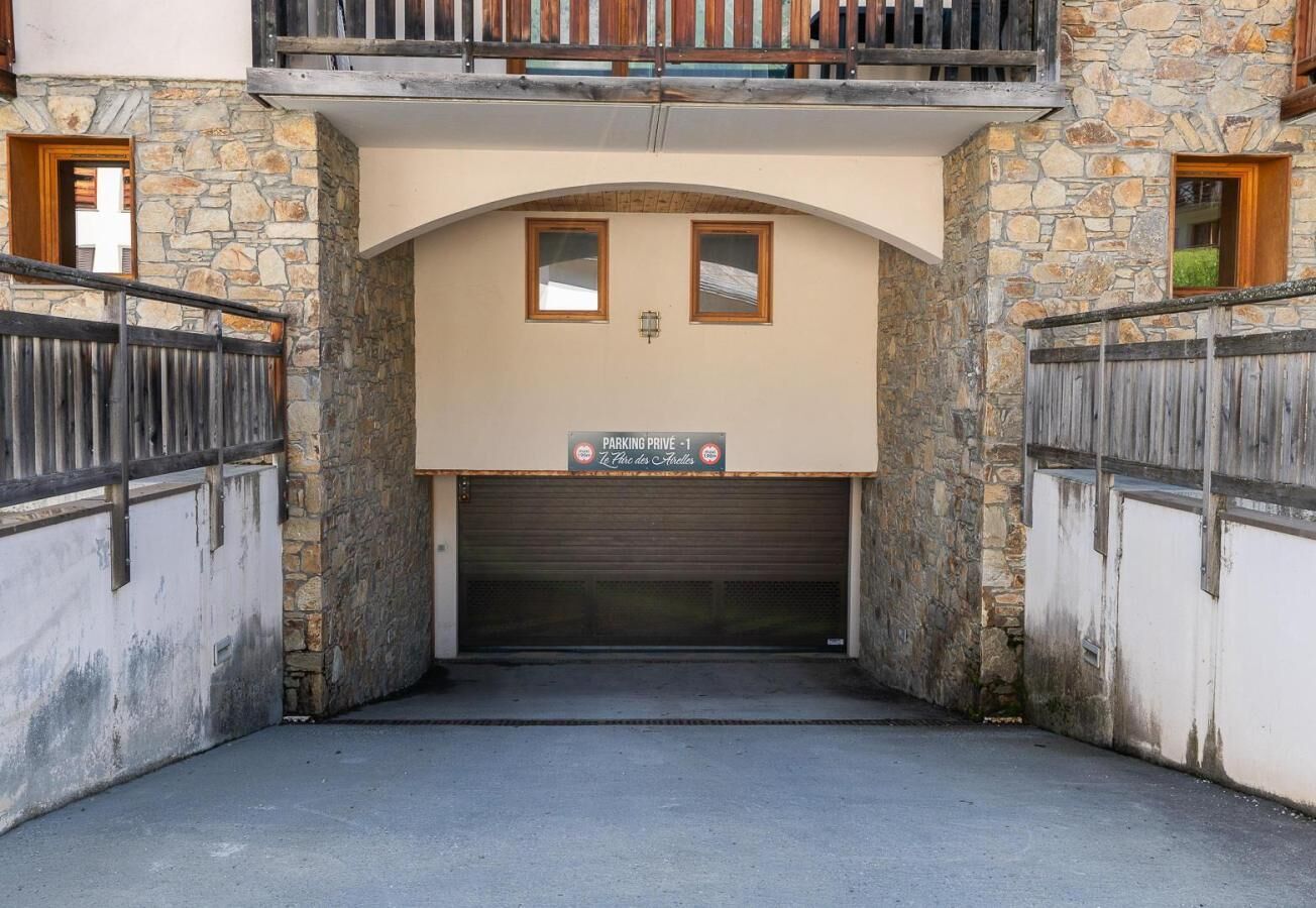 A stone building with a closed garage door, a sign above the door, and a balcony with wooden railings.