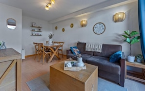 A modern living room with a dining area, featuring a sofa, coffee table, and a dining table with chairs. - 20m from ski lifts, floor -1, swimming pool, sauna, terrace, tv, ski locker, 34m², Les Orres (Les Orres)