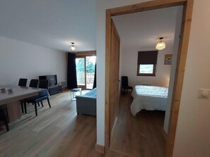 A room with a wooden floor, a bed, a desk with a chair, a television, and a window. - 50m from ski slopes, 4th floor, balcony, tv, 54m², Valmorel (Les Avanchers-Valmorel)