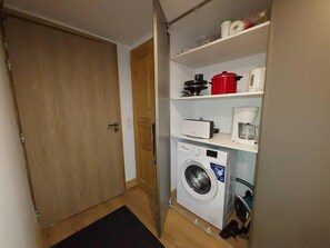 A compact laundry area with a washing machine, a dryer, and a coffee maker on a shelf. - 50m from ski slopes, 4th floor, balcony, tv, 54m², Valmorel (Les Avanchers-Valmorel)