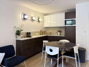 A compact kitchen with a dining area, featuring a round table, chairs, and a microwave above the counter. - Ski-in/ski-out & foot of the slopes, 5th floor, balcony, tv, 40m², Les Orres (Les Orres)