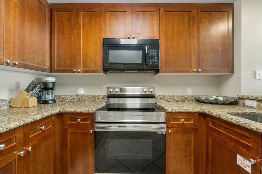 A kitchen with wooden cabinets, a stainless steel oven, a microwave, and granite countertops.