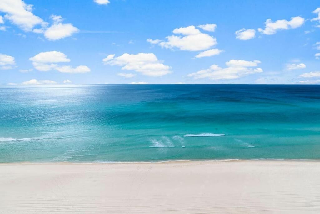 A beach with clear blue water and a sandy shore.