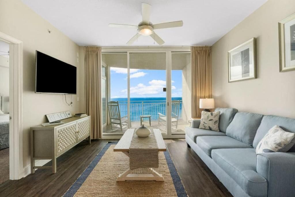 Une chambre d’hôtel avec balcon, une télévision à écran plat, un canapé, une table basse et une vue sur l’océan.
