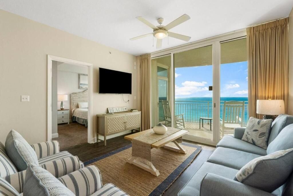 Ein Hotelzimmer mit Balkon, Fernseher, Sofa, Couchtisch und Bett.
