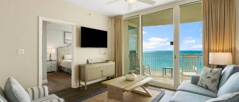 Ein Hotelzimmer mit Balkon, Fernseher, Sofa, Couchtisch und Bett.