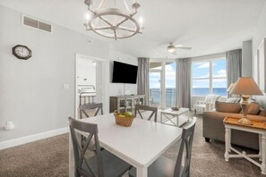 Ein modernes Wohnzimmer mit Essbereich, einem Fernseher und Blick aufs Meer.