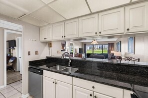 Cuina amb armaris blancs, tauleig de granit negre i rentaplats.