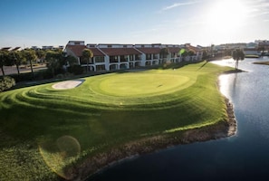 Camp de golf amb una bassa, envoltat d'edificis residencials.