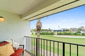 A balcony with a view of a green lawn and buildings in the distance. - Edgewater Golf Villas (Panama City Beach)