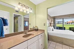 A hotel room with a bathroom featuring a sink, mirror, and towel rack. - Edgewater Golf Villas (Panama City Beach)