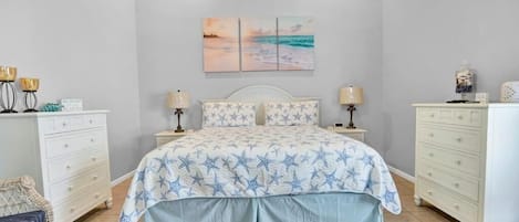 A bedroom with a bed, two nightstands, a dresser, a chair, and a ceiling fan.