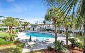A hotel with a swimming pool, lounge chairs, palm trees, and a building with multiple floors. - Horizon South (Panama City Beach)