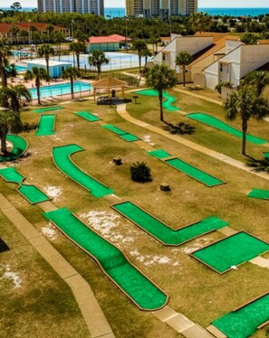 A golf course with multiple green areas and a pool. - Horizon South (Panama City Beach)