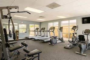 Een fitnessruimte met loopbanden, elliptische trainers en gewichthefapparatuur.
