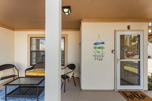 A covered outdoor seating area with wicker furniture and a glass table. - Horizon South (Panama City Beach)