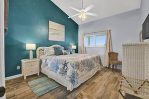 A bedroom with a bed, nightstands, a ceiling fan, a window with curtains, and a chair. - Nautical Watch (Panama City Beach)