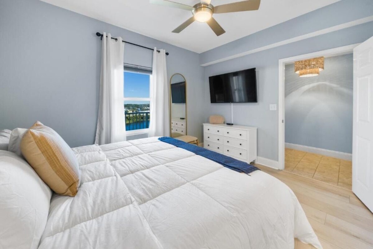 A bedroom with a bed, a dresser, a television, and a ceiling fan.